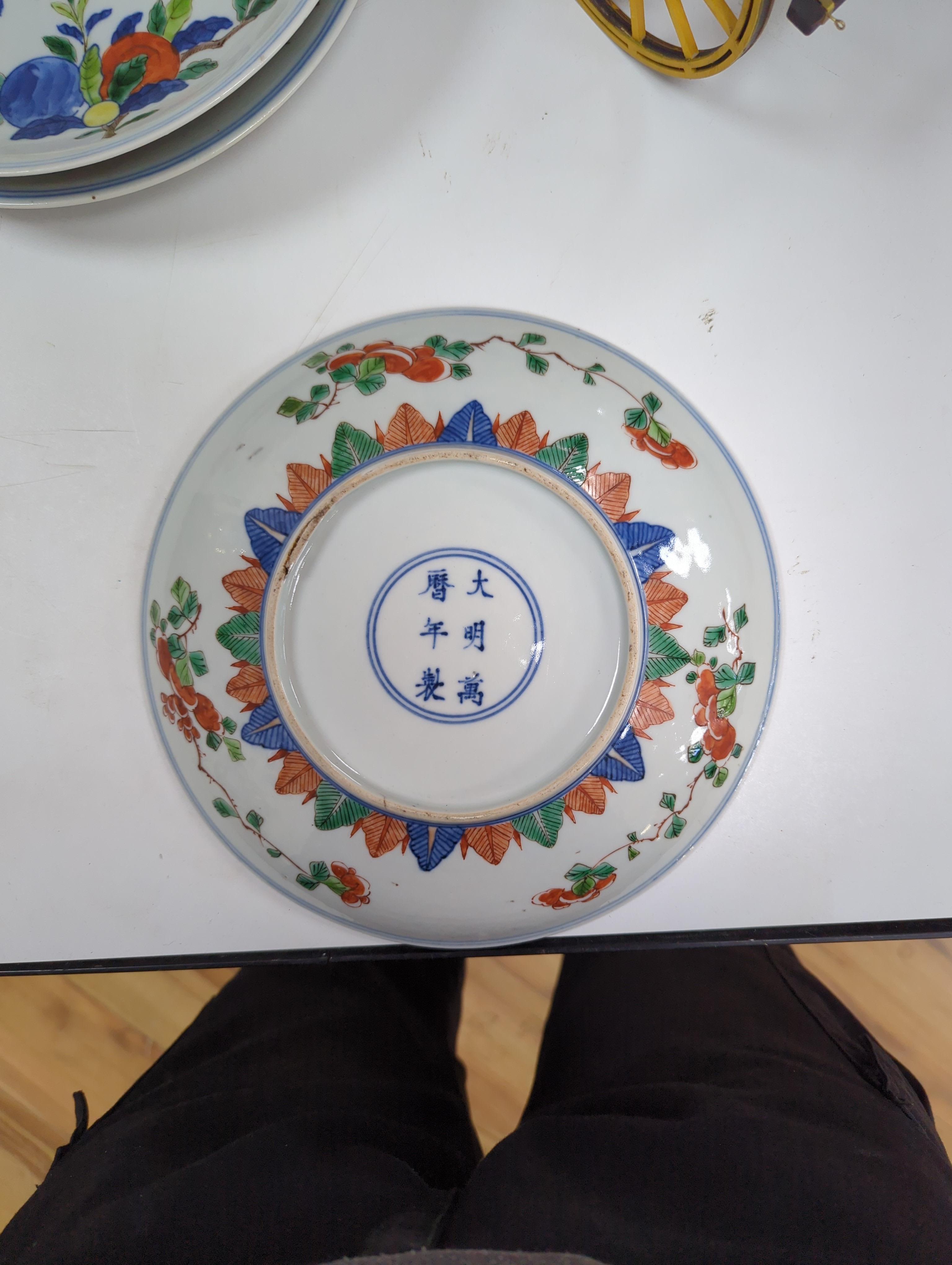 An 18th century Chinese famille rose bowl and a group of five Chinese wucai plates, each decorated with fruit, the bowl 23cm in diameter